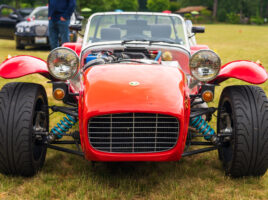 Front view of a red and silver roadster in a grassy field