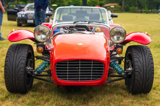 Front view of a red and silver roadster in a grassy field